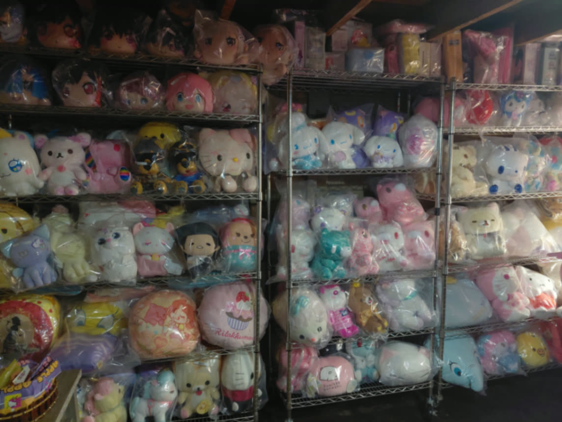 Floor-to-ceiling wall of sealed anime and Sanrio plush prizes on chrome shelves