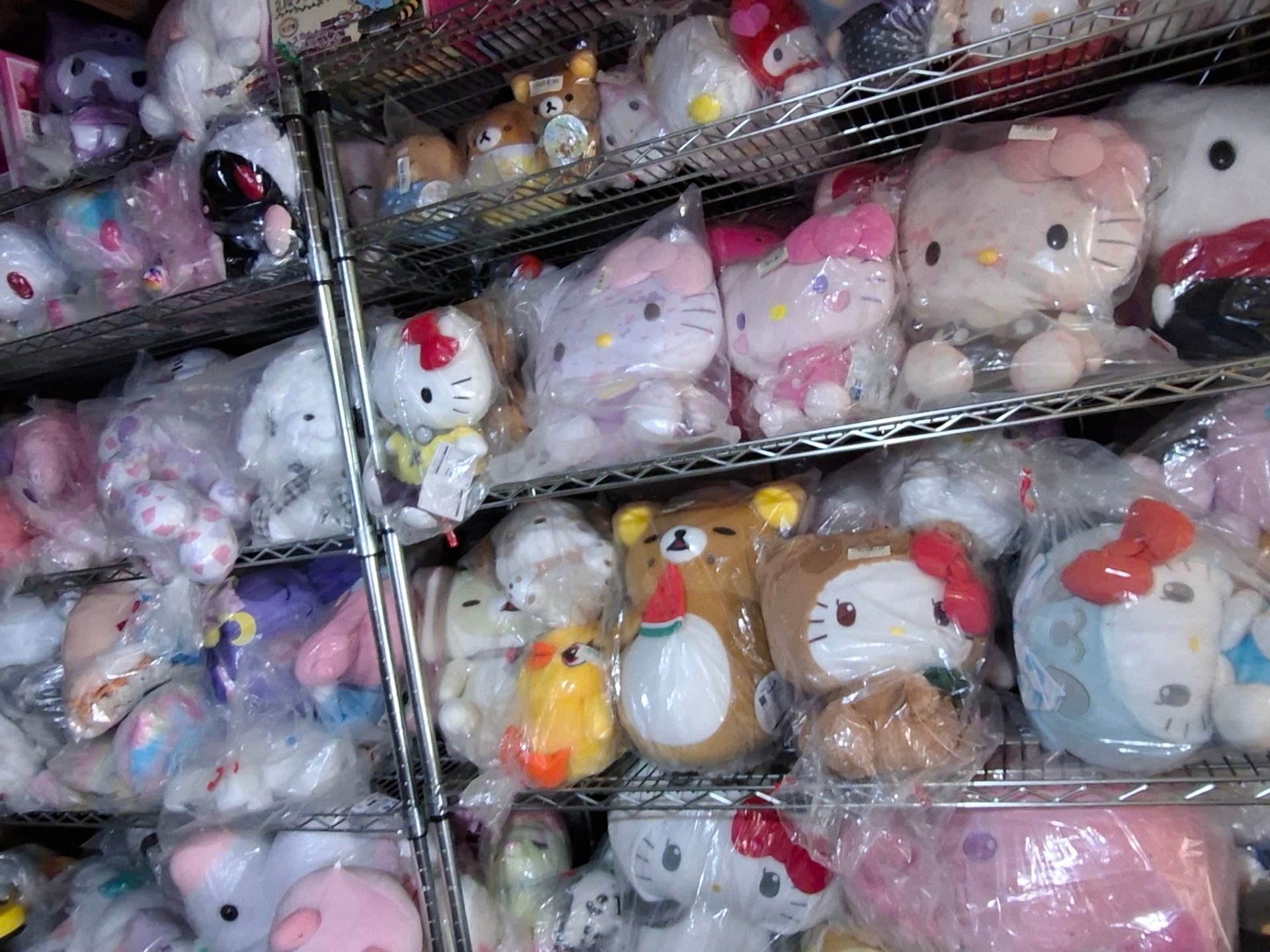 Close-up of stacked sealed Sanrio and San-X plush prizes on the first floor shelves