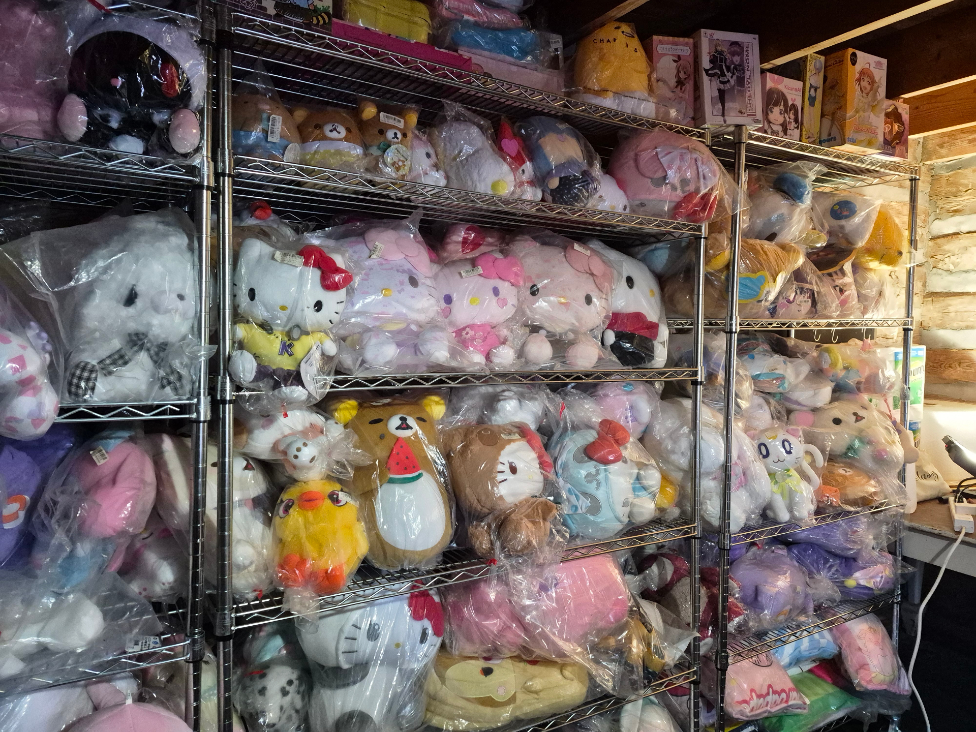 Full aisle of chrome shelving stacked with sealed Japanese arcade plush inside the cottage