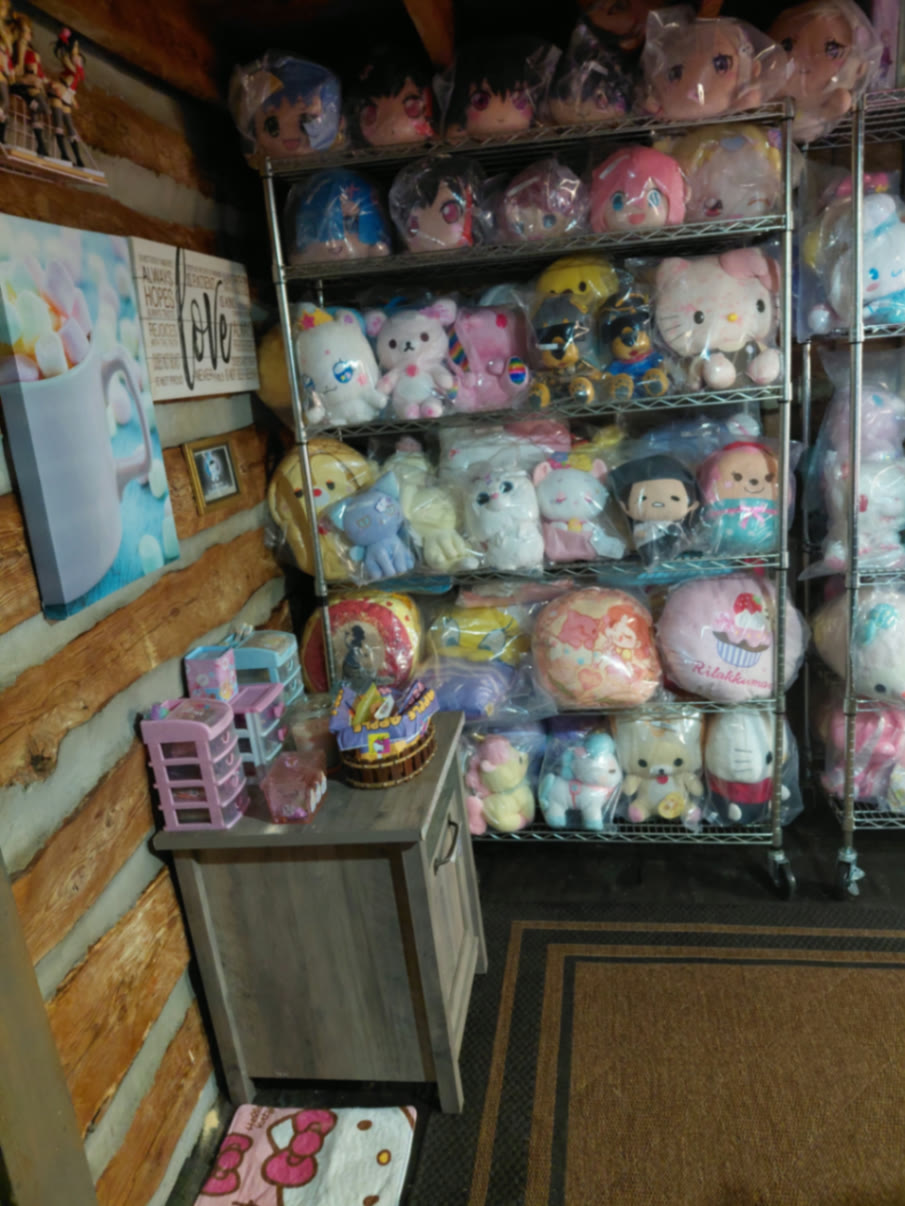 Log wall nook with a marshmallow cocoa canvas, LOVE sign, and shelves of sealed plush beside a wooden cabinet