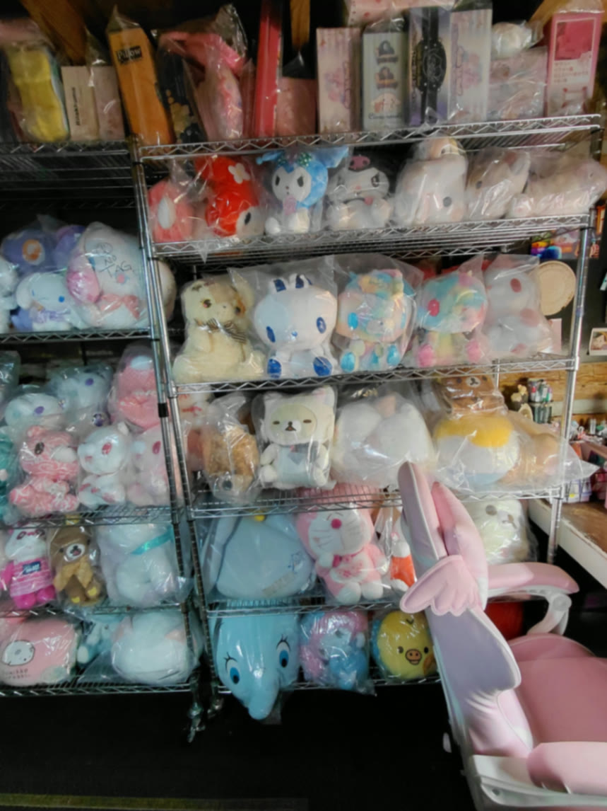 Pastel pink bunny-eared chair tucked beside shelves of sealed Japanese plush prizes